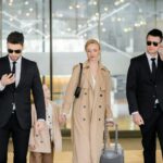 personal security concept, two bodyguards in suits and sunglasses protecting blonde woman