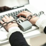 photo of woman locked in chain typing on laptop